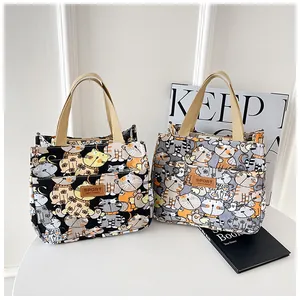 Detail van canvas lunchtassen met kattenprint, sport-lederen patch en geweven hengsels