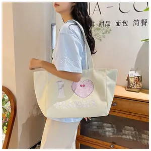 Lifestyle shot of large off-white canvas tote bag with pink heart and I PLUSHY print