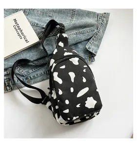 Close-up of cow print canvas chest bag with adjustable strap on denim background