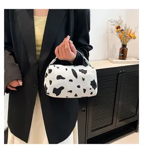 Detail of cow print corduroy bucket bag held by a model in a minimalist urban setting