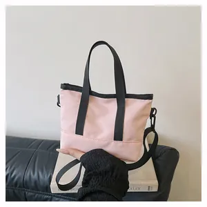 Détail d'un mini sac rose et noir avec bandoulière amovible sur un banc minimaliste