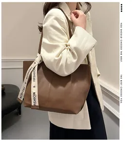 Detail of dark brown tote bag with fashion ribbon strap worn with beige blazer