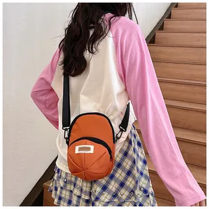 Detail of an orange nylon mini crossbody bag with zipper pocket and adjustable strap