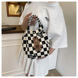 Detail of knit tote bag featuring black and white checkerboard pattern and rabbit patch