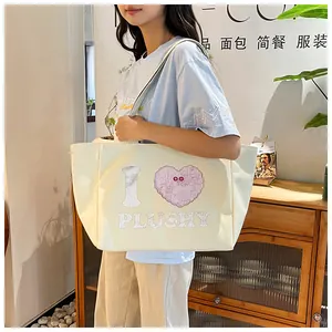 Close-up of cream canvas tote bag with cute plushy heart print and wide shoulder strap