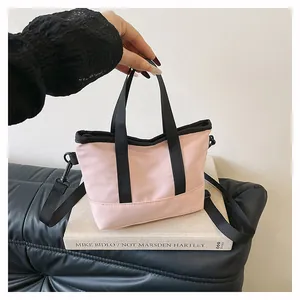 Détail du mini sac à bandoulière rose avec poignées noires et bandoulière amovible