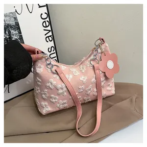 Detail of pink canvas tote featuring floral embroidery and flower-shaped leather charm