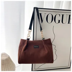 Detail of brown corduroy tote bag showing thick texture, chain strap, and fashion label