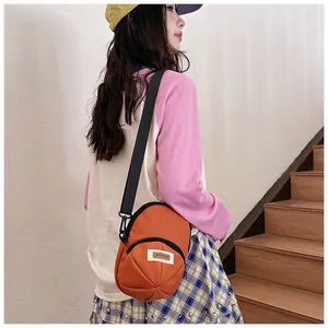 Close-up of an orange nylon crossbody bag with adjustable strap shown in street style scene