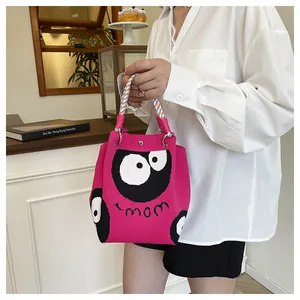 Close-up of fuchsia knit tote bag with monster eyes pattern and colorful braided handles