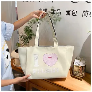 Detailed view of cream canvas tote bag featuring large I letter and plush pink heart print