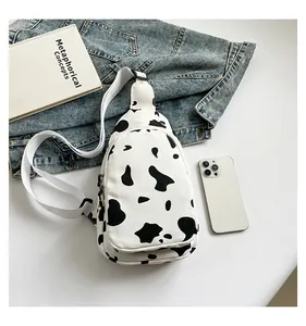 Detail of canvas chest bag featuring black and white cow print and adjustable strap