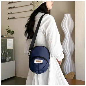 Close-up of navy blue canvas hat-shaped crossbody bag with adjustable strap on a model
