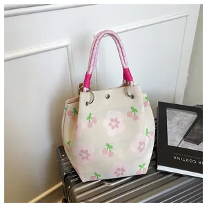 Detail of knit tote bag featuring pink floral cherry patterns and woven rope handle