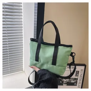 Détail d'un mini sac cabas en toile vert clair avec bandoulière noire réglable