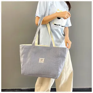 Detail of blue striped corduroy tote bag featuring woven straps and logo patch