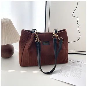 Detail of fashion brown corduroy tote bag showing metal chain strap and leather patch