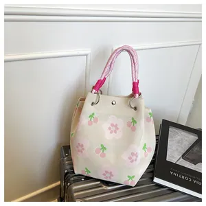 Detailed close-up of knitted tote bag with pink cherry pattern and rope handles