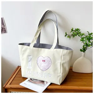 Detail of canvas tote bag showing interior grey striped lining and pink plushy heart print