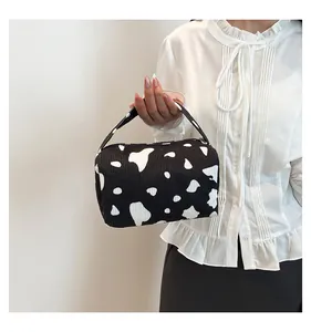 Macro detail of cow print corduroy makeup bag with textured fabric and hand strap