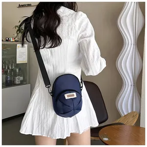 Detail of navy nylon crossbody bag with pleated design and adjustable strap on a model