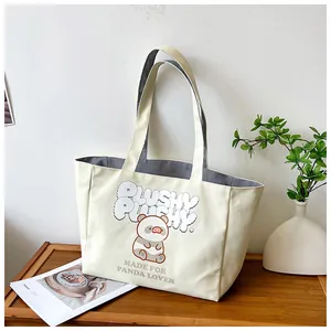 Detail of canvas tote bag showing panda print and striped lining on wooden tray