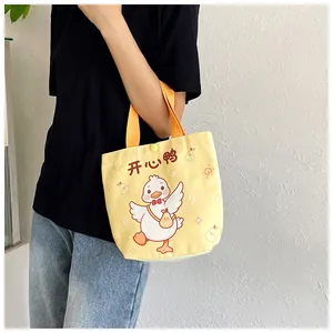 Detail view of yellow canvas gift bag with cartoon duck print held by a model