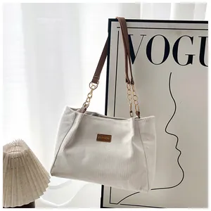 Detail of white corduroy tote bag with fashion leather patch and chain strap