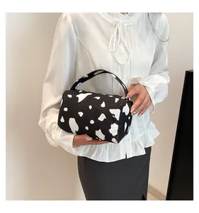 Detail of a cow print corduroy barrel bag with a sturdy handle and top zipper closure