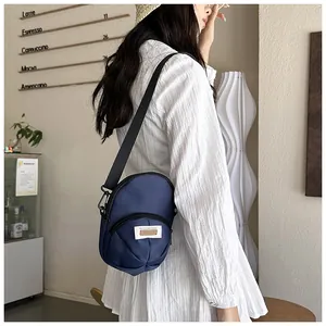 Detail of a navy blue nylon crossbody bag with front zipper pocket and adjustable strap