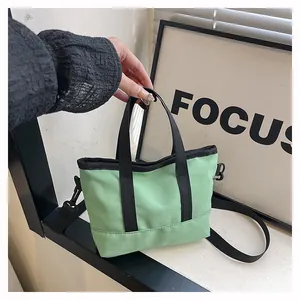 Détail du mini sac en toile vert clair avec sangles noires et bandoulière amovible
