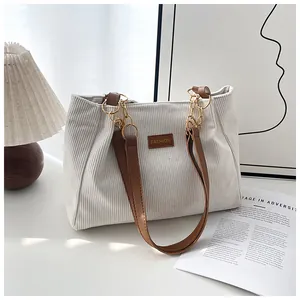 Detail of off-white corduroy tote with brown leather strap and gold chain accent