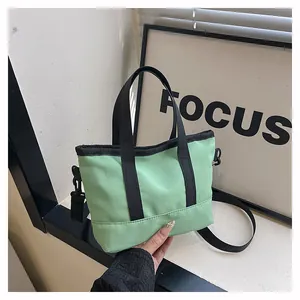 Gros plan du mini sac fourre-tout vert montrant la texture nylon et les anses noires