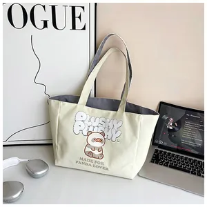 Close-up of cute panda canvas tote bag with laptop and headphones on a stylish desk