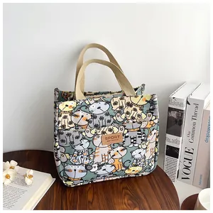 Detail van de canvas tas met kattenprint, blauwe stof en modieus leren label erop