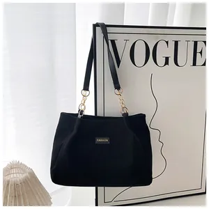 Close-up of black corduroy tote bag featuring a gold chain strap and Fashion patch
