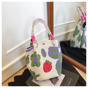 Detail of knitted bucket bag with floral strawberry print and colorful rope handle