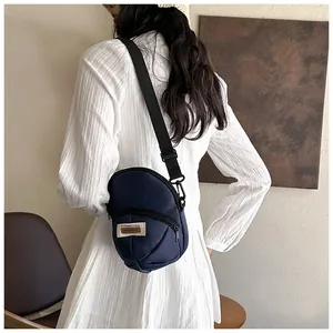 Detail shot of navy nylon crossbody bag on model showing adjustable strap and size