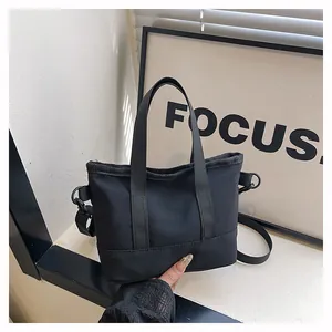 Détail du mini sac cabas noir en toile avec doubles poignées et bandoulière amovible