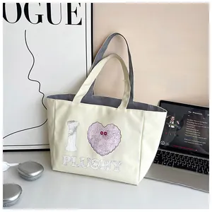 Detail of cream canvas tote bag featuring plush heart print and red button accents