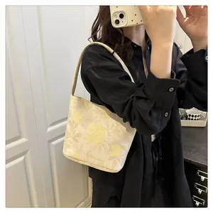 Close-up of Chinese style bucket bag with floral embroidery and long handles in hand