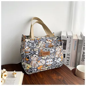 Detail van canvas lunchtas met kattenpatronen en lederen decoratieve merkpatch
