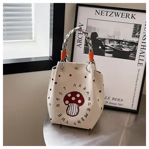 Detail of beige knit bucket bag with mushroom pattern and multi-color woven handles