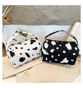 Detailed view of two corduroy cow print organizer bags with zippers and handles