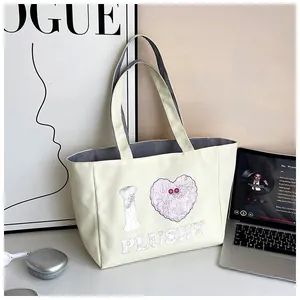 Detail view of cream canvas tote bag featuring heart print in a cozy office setting