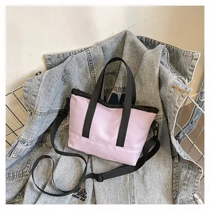 Détail du mini sac cabas en toile lilas avec sangles noires sur fond de jean bleu