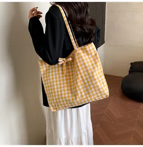 Detail of yellow gingham tote bag featuring a decorative bow on the shoulder strap