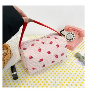 Detailed macro view of pink corduroy pouch with red strawberry print and zipper