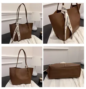 Detail view of large dark brown tote bag showing stitching and decorative ribbon
