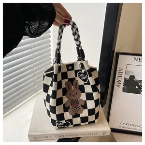 Detail of checkered knit tote bag with a cute brown cartoon rabbit and text jacquard